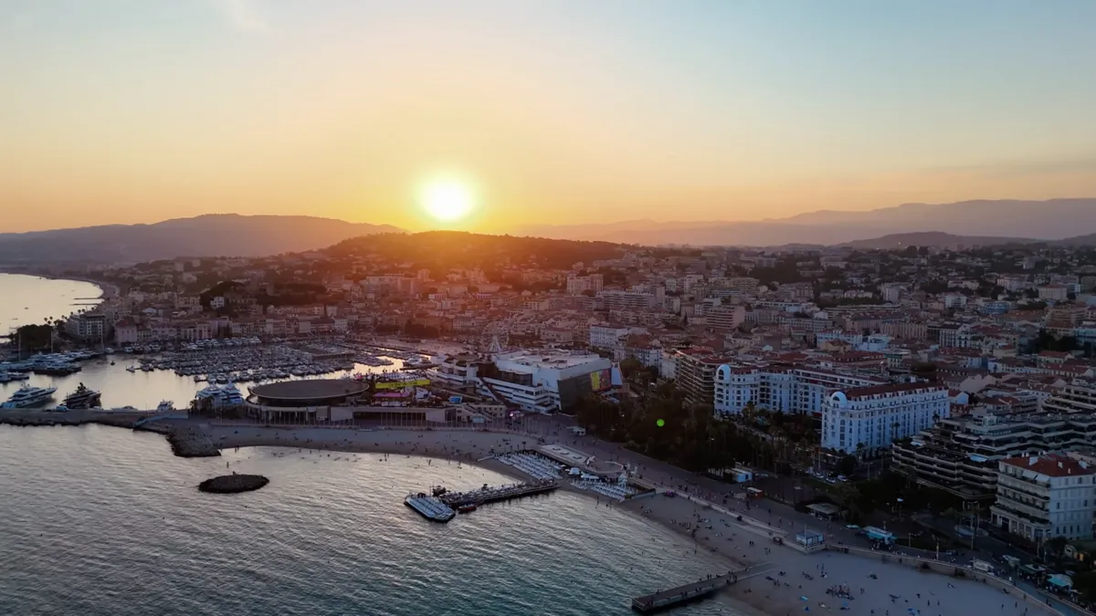 Vue aérienne de la Croisette à Cannes au coucher du soleil, avec le Palais des Festivals, la plage et le port