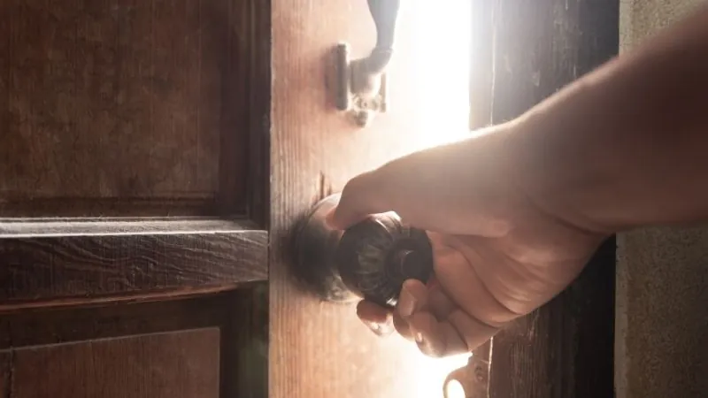 Main sur la poignée d'une porte d'entrée, au moment de faire entrer un serrurier